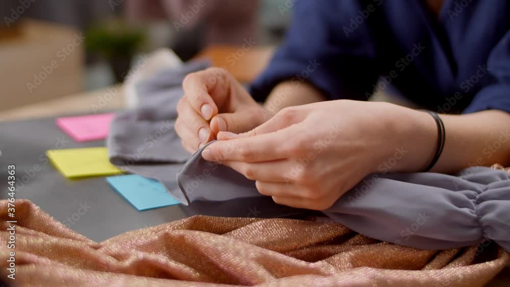 Beautiful woman fashion designer is working in her studio apartment on a new dress Beautiful woman fashion designer is working in her studio apartment on a new dress