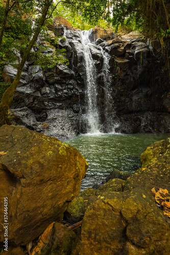 Waterfall landscape. Beautiful hidden waterfall in tropical rainforest. Foreground with big stones. Fast shutter speed. Sing Sing Angin waterfall, Bali, Indonesia