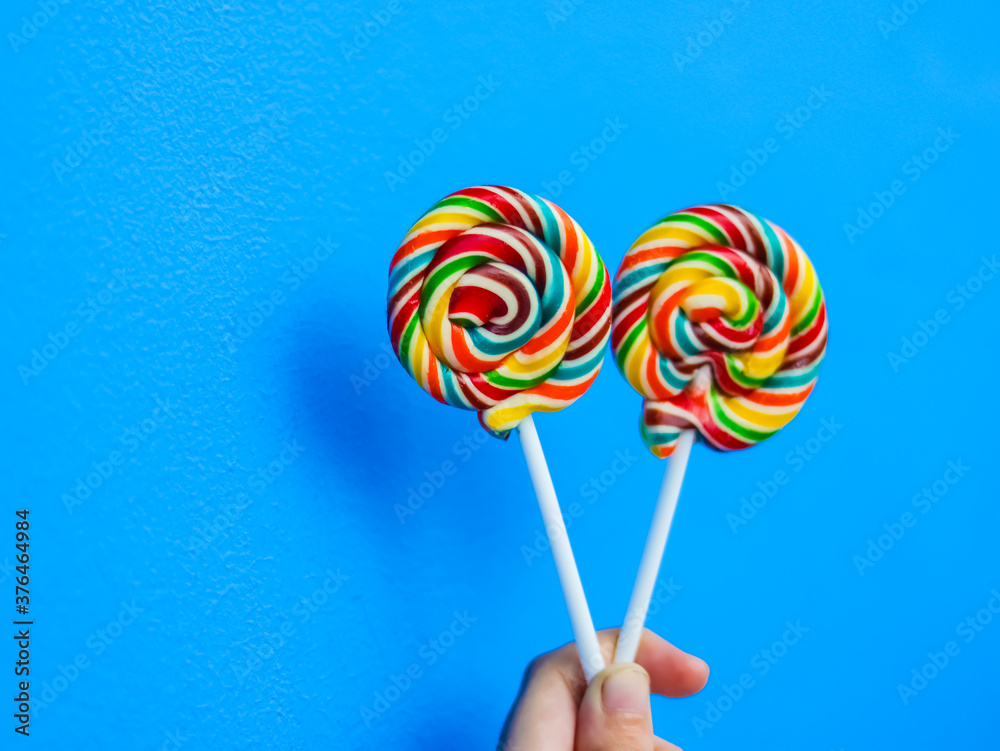 colorful lollipop in hand on blue background colorful lollipop in hand on blue background