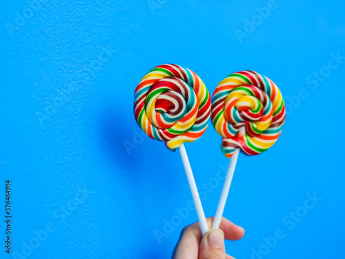 colorful lollipop in hand on blue background © ARH2001