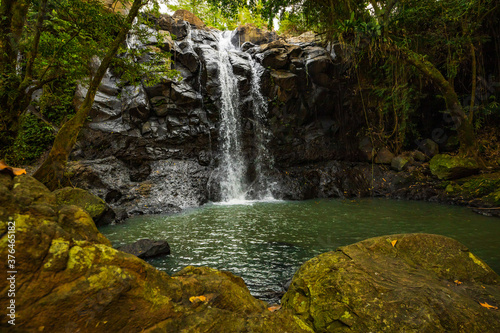 Waterfall landscape. Beautiful hidden waterfall in tropical rainforest. Foreground with big stones. Fast shutter speed. Sing Sing Angin waterfall  Bali  Indonesia