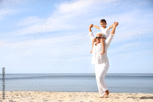 Cute little boy with grandfather spending time together on sea beach