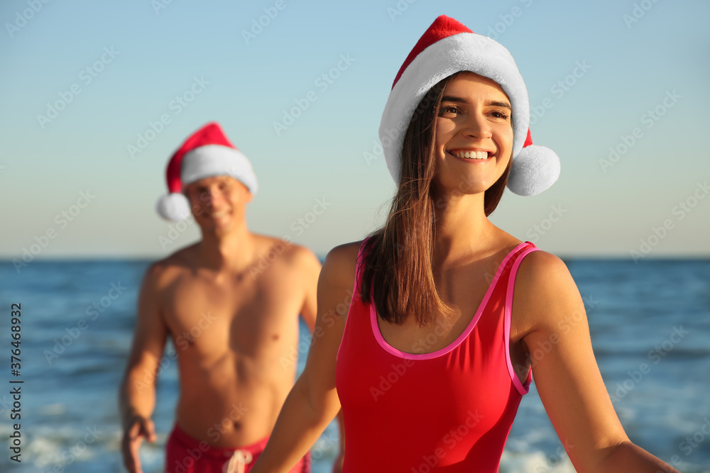 Happy couple with Santa hats together on beach. Christmas vacation Happy couple with Santa hats together on beach. Christmas vacation