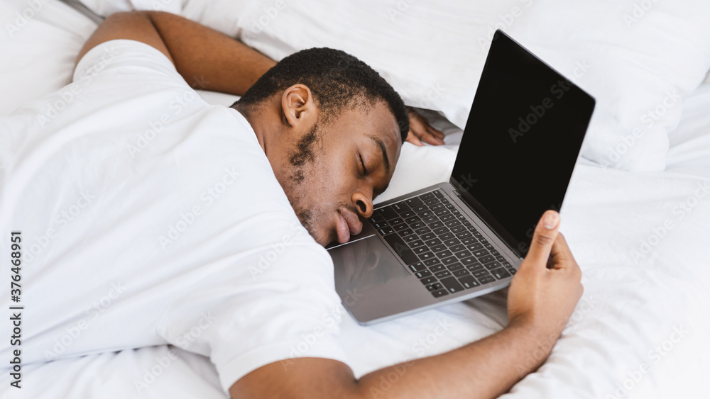 Exhausted Black Guy Sleeping On Laptop Lying In Bed At Home Exhausted Black Guy Sleeping On Laptop Lying In Bed At Home