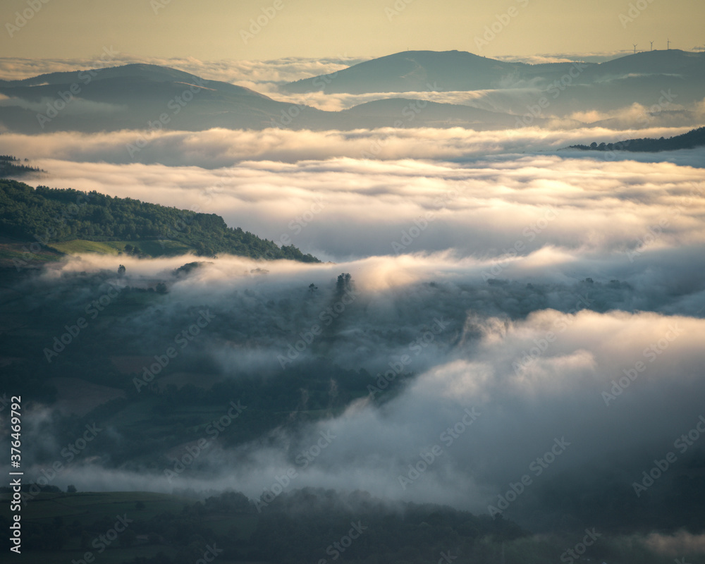 Fototapeta premium Misty sunrise alternating forested mountains and green valleys