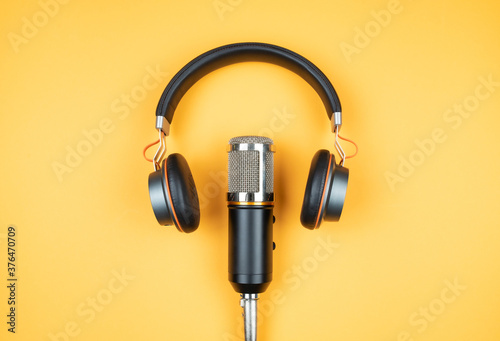 podcasting concept, directly above view of headphones and recording microphone on orange background © Christian Horz