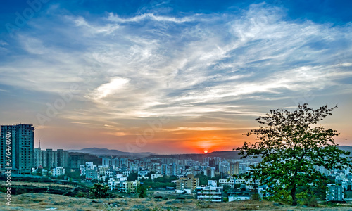 Sunset behind tall buildings in a rapidly growing city-Pune, Maharashtra, India. © lalam