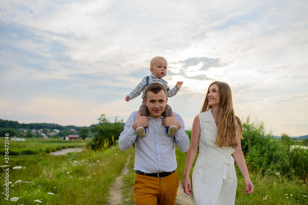 Family for a walk. The father carries his one-year-old son on his shoulders. Family for a walk. The father carries his one-year-old son on his shoulders.