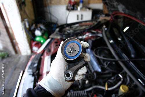 Car timing belt tensioner in hand of mechanic