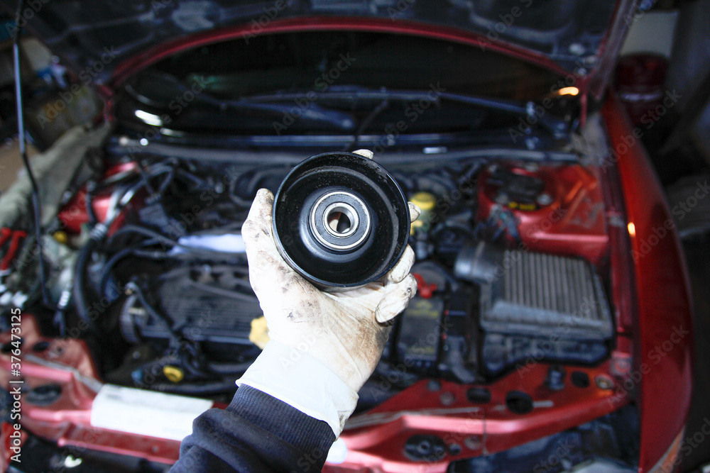 tension roller of the generator in the hand of the master in the garage.
