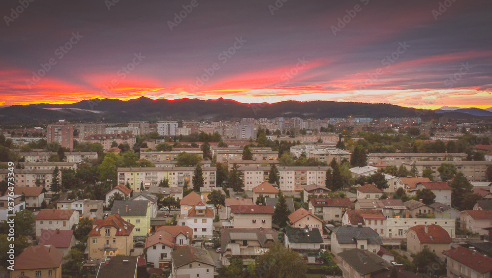 Evening panorama of Siska, a suburban part of Ljubljana, capitol of Slovenia, with a sunset visible after a thunderstorm. Dark clouds above rich colorful sunset and a beautiful skyline and cityscape