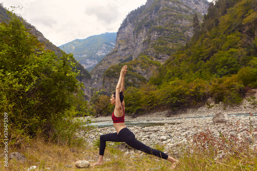 Yoga classes in nature. A woman does yoga in the mountains, near a mountain river flows. The concept of playing sports alone. Social exclusion