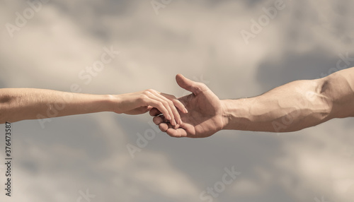 Giving a helping hand. Hands of man and woman on blue sky background. Lending a helping hand. Solidarity, compassion, and charity, rescue © Yevhen
