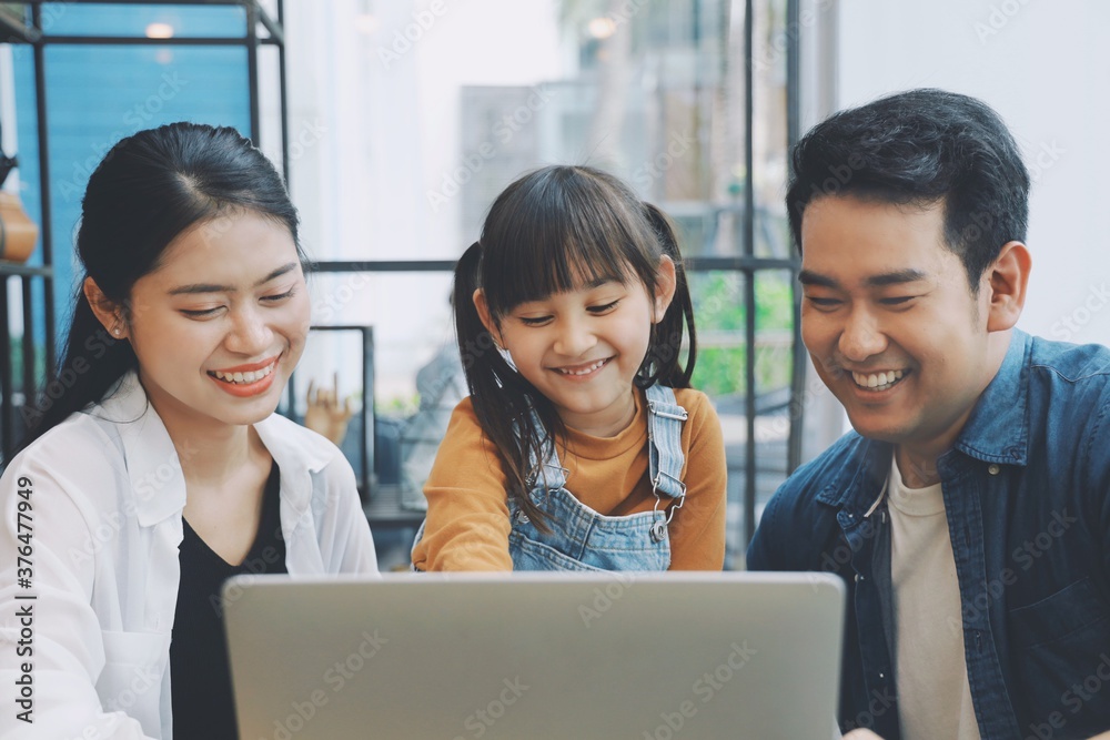 Happy family using laptop together at living room,Parents watching movie with child. Happy family using laptop together at living room,Parents watching movie with child.