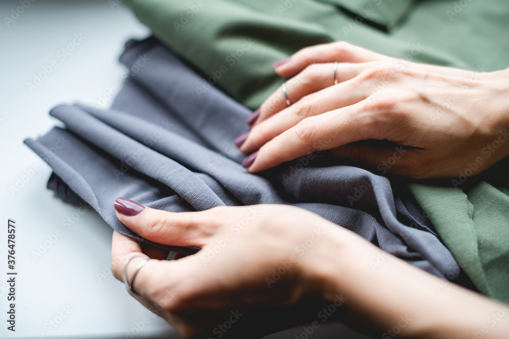 Cropped view of designer holding fabric on grey surface 