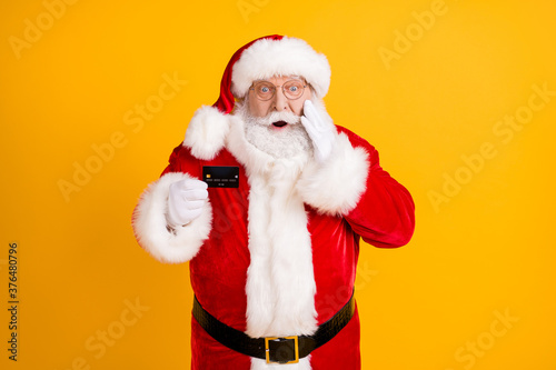 Photo fat grey white beard hair santa claus impressed credit card x-mas christmas season shopping tradition sales pay touch white gloves wear cap headwear isolated bright shine color background