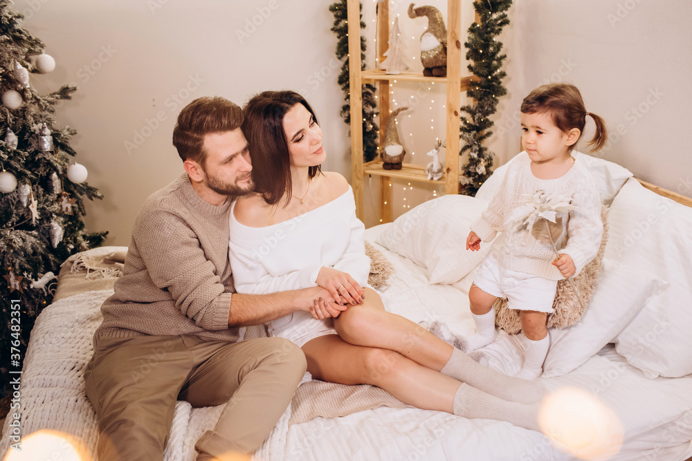 young parents with a small daughter against the background of the Christmas tree, Merry Christmas, family portrait young parents with a small daughter against the background of the Christmas tree, Merry Christmas, family portrait
