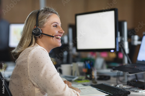 Young businesswoman wearing headset talking at modern office