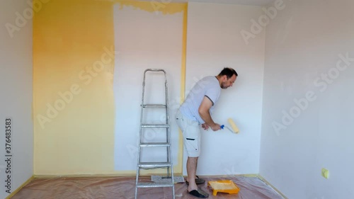 Time lapse of a man painting white walls in yellow color.