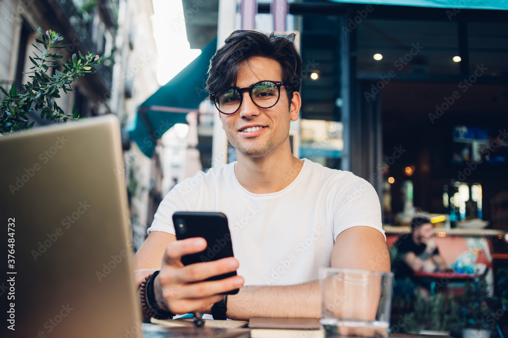 Cheerful man messaging on smartphone at cafe in Barcelona Cheerful man messaging on smartphone at cafe in Barcelona