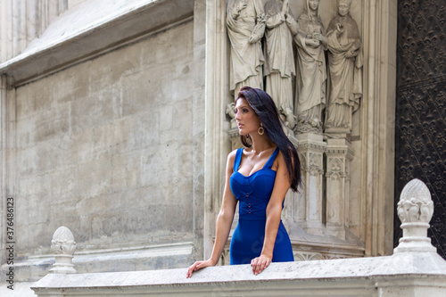 Young beautiful stylish girl in blue summer dress walking and posing in an old city center scene in Vienna, Austria
