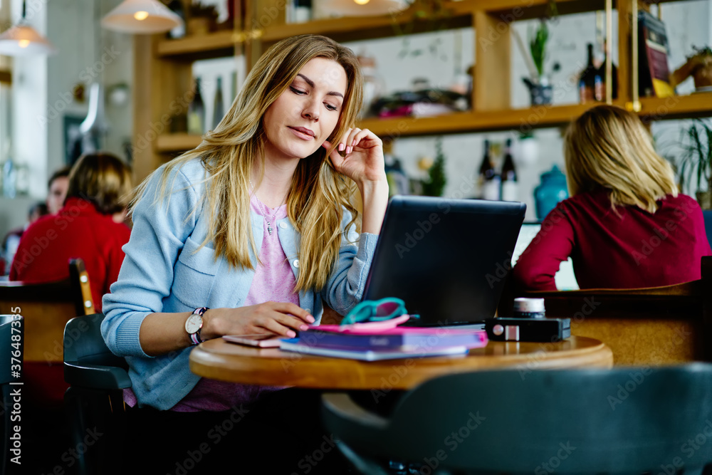 Busy young lady working on laptop in cafe Busy young lady working on laptop in cafe
