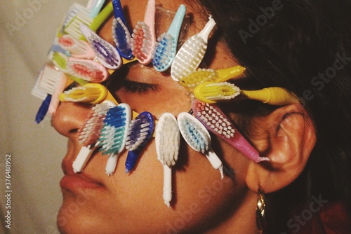 Young woman with toothbrush heads around her eyes, an abstract art photograph on dental health and white teeth *2