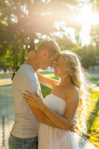 Happy and young pregnant couple hugging in nature