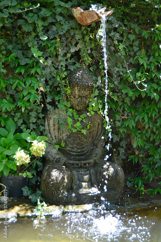 BUDDHA STATUE IN A BOTANICAL GARDEN FOUNTAIN