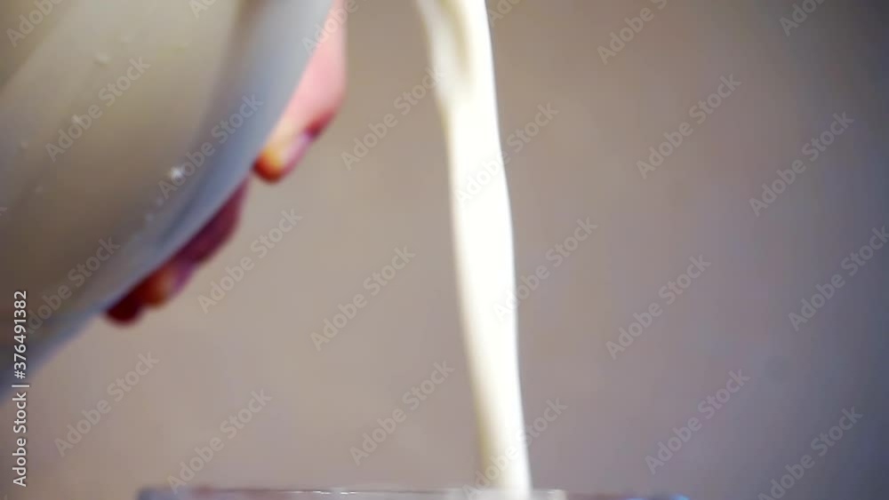 milk is poured from a plastic bottle into a glass.close-up. milk is poured from a plastic bottle into a glass.close-up.