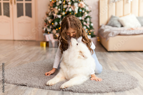 Christmas Child girl with dog Samoyed. New Year at home