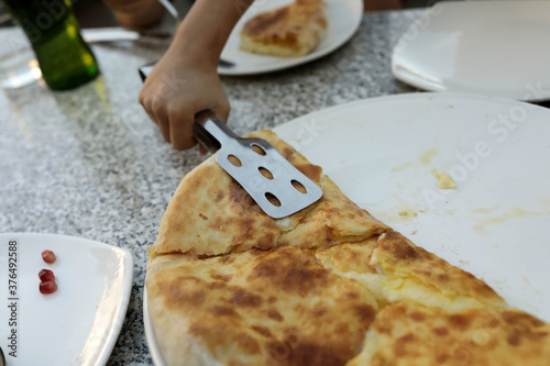 Kid takes Megrelian Khachapuri from plate photo