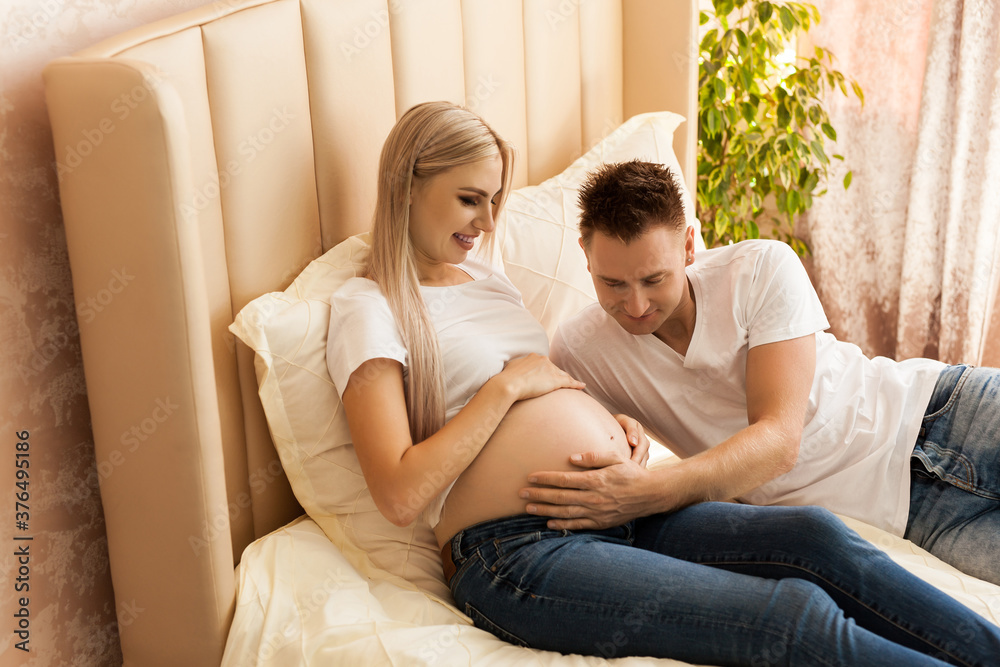 happy man hugging pregnant woman at home