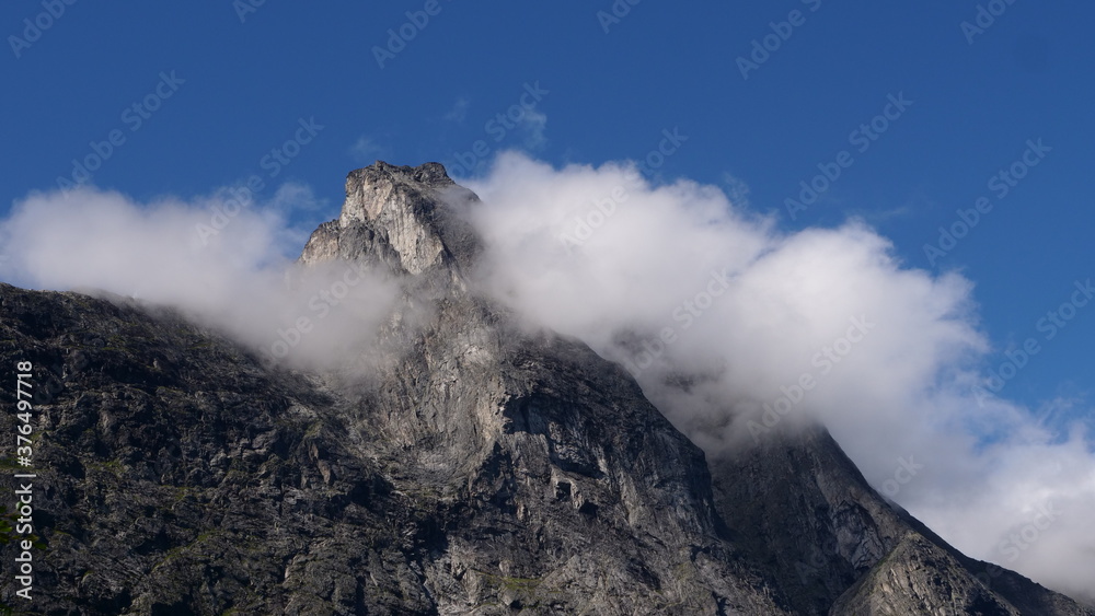 Fototapeta premium The top of a mountain surrounded by clouds near trollstigen
