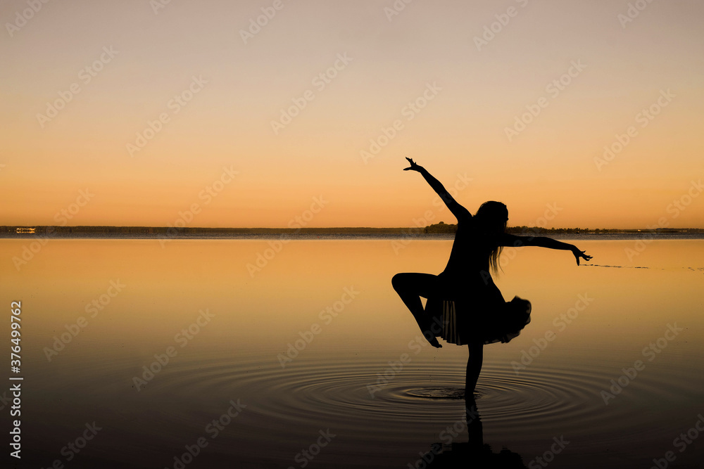 Black silhouette of a woman dancing in the water. Lake Svityaz, Volyn, Ukraine. Copy space. Minimalism. 