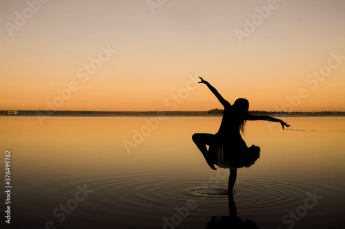 Black silhouette of a woman dancing in the water. Lake Svityaz, Volyn, Ukraine. Copy space. Minimalism. 