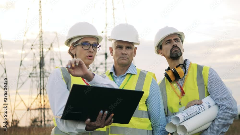 People work with laptop, checking power lines in a field. People work with laptop, checking power lines in a field.