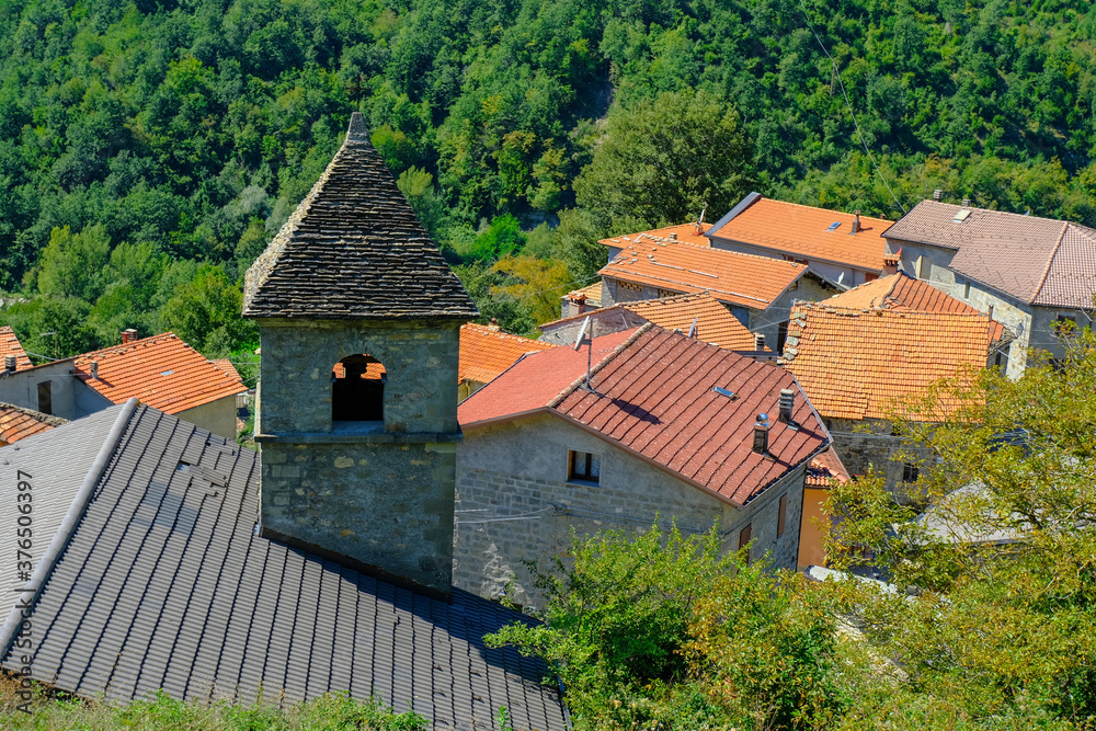 Red, orange roofs. church in the village across green mountains close-up. Scenery rural view. Background. Copy space. Italy, Emilia-Romagna, Cecciolo Red, orange roofs. church in the village across green mountains close-up. Scenery rural view. Background. Copy space. Italy, Emilia-Romagna, Cecciolo