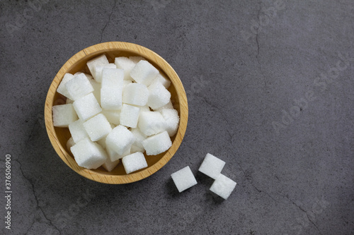 Wooden bowl with sugar on dark background