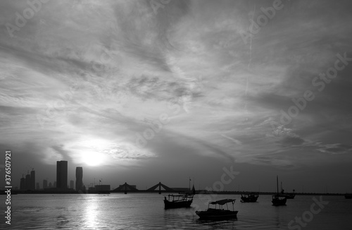 Boats and Bahrain skyline with dramatic sky during sunset