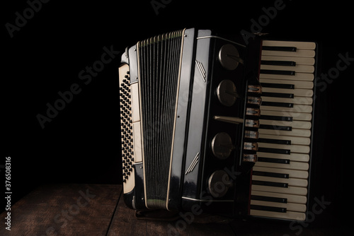 Papier peint Old accordion on rustic wooden surface with black background and Low key lighting, selective focus