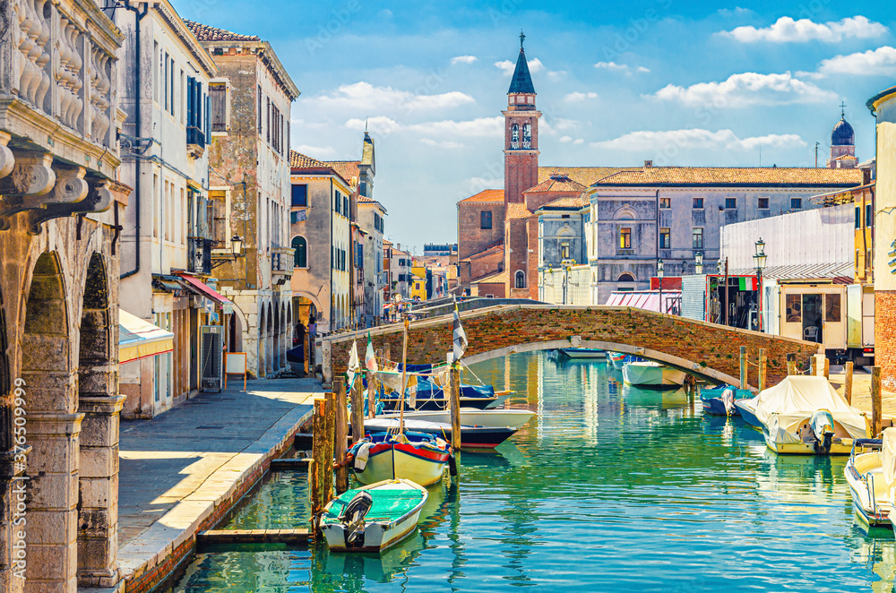 Chioggia cityscape with narrow water canal with moored multicolored boats, old buildings