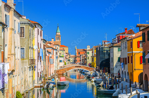 Chioggia cityscape with narrow water canal Vena with moored multicolored boats between old colorful buildings © Aliaksandr