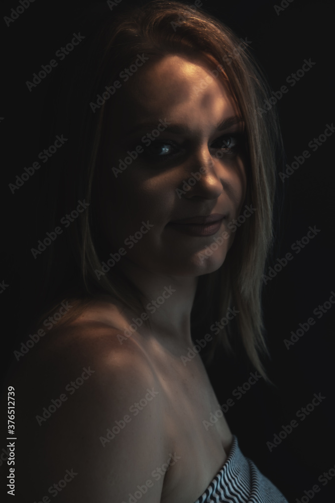 Beautiful mid adult woman with interesting pattern of light and shadow on her face. Beauty female portrait.