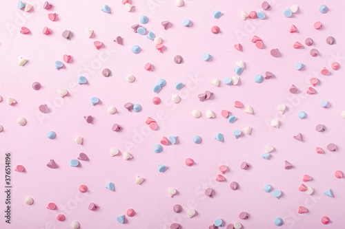 background candy sweets or pastel colored chocolate chips on a pink background that form a nice texture