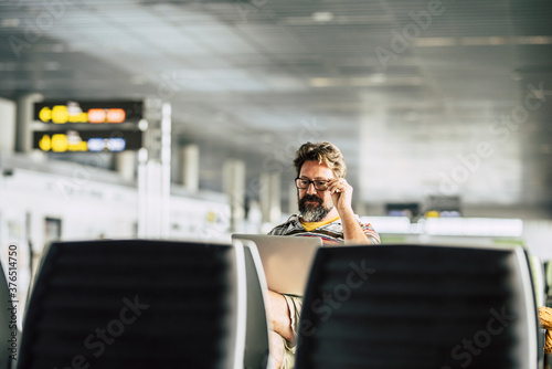 Adult caucasian man work at a laptop computer waiting his flight in the airport gate - concept of digital nomad and technology job related - modern people and internet connection