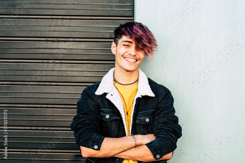 Cheerful portrait of caucasian young man teenager smiling at the camera - two colors background gray and white - urban people style having fun in outdoor photo