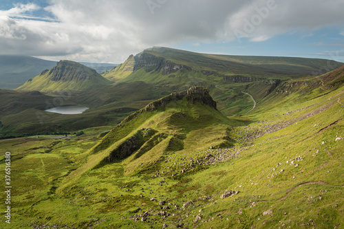 Scenic view of rock formations in Quiraing, Isle of Skye, Scotland. Beautiful area of grassy mountains covered by blooming heather in summer, hidden lochs and steep cliffs