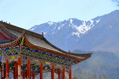 Part of an ancient chinese-style gazebo in the backdrop of snow-covered Qilian Mountains in the city of Zhangye  Gansu  China. Zhangye is one of points along the ancient silk road.