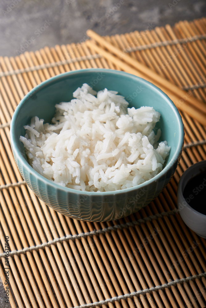 Rice in a porcelain bowl, with Japanese chopsticks, soy sauce, served on a gray stone table Rice in a porcelain bowl, with Japanese chopsticks, soy sauce, served on a gray stone table